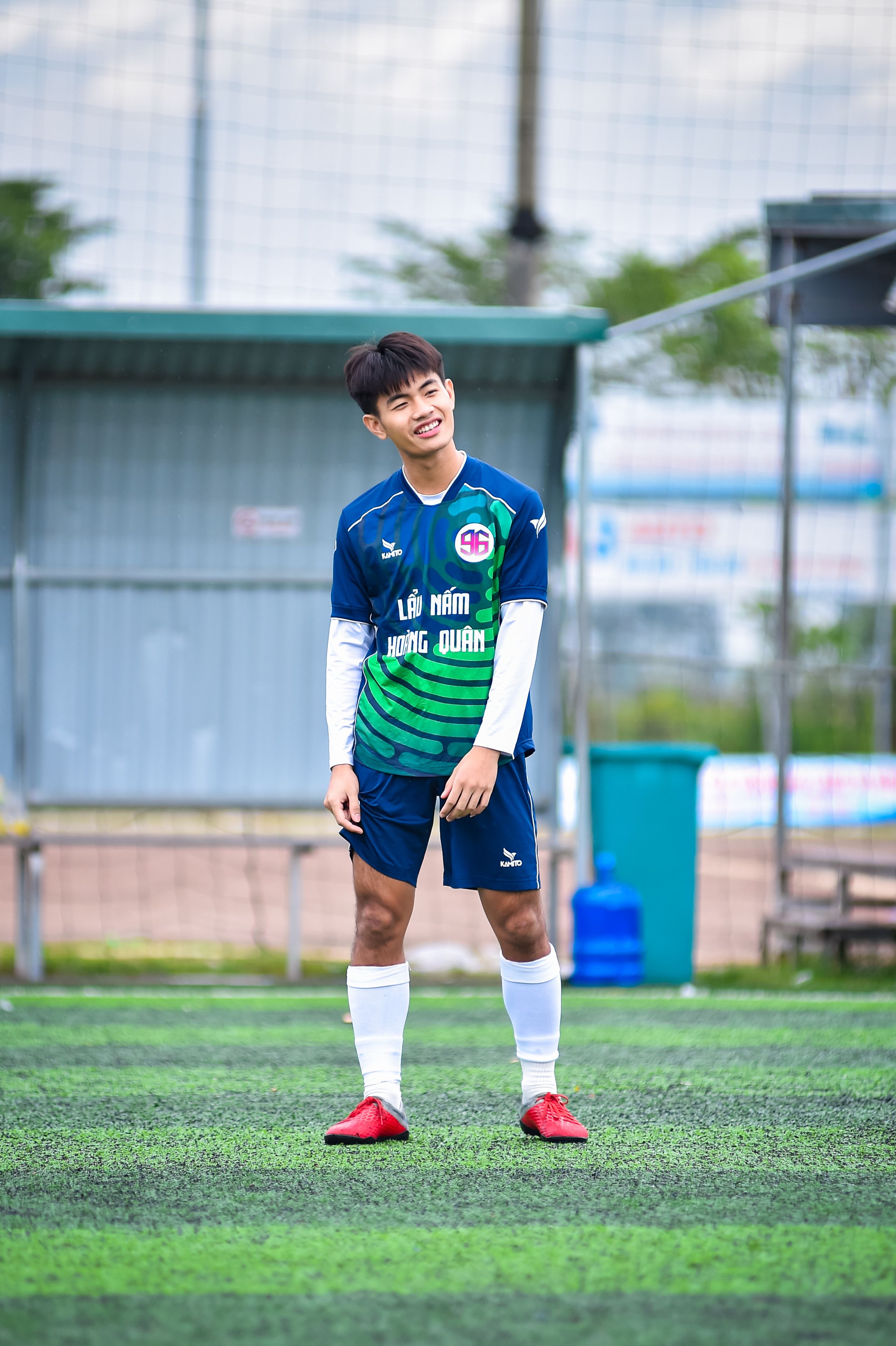 A teenage football player smiles on an artificial turf field in Vietnam.