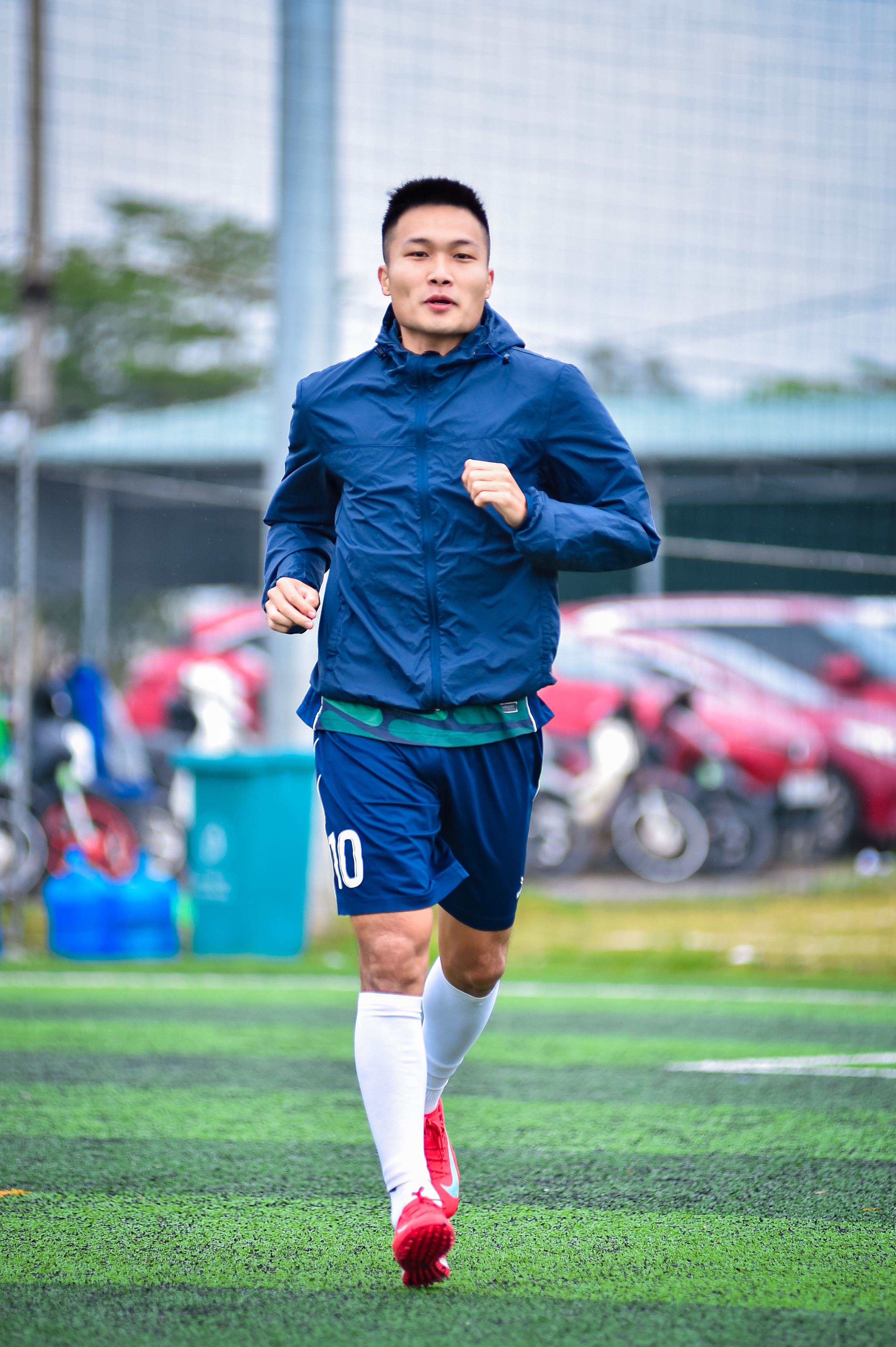 Athlete running during football training session on synthetic turf in Hanoi, Vietnam.