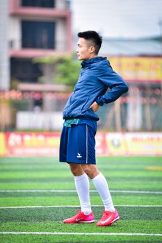 Side profile of a young man in sportswear standing on a football field in Hanoi, Vietnam.