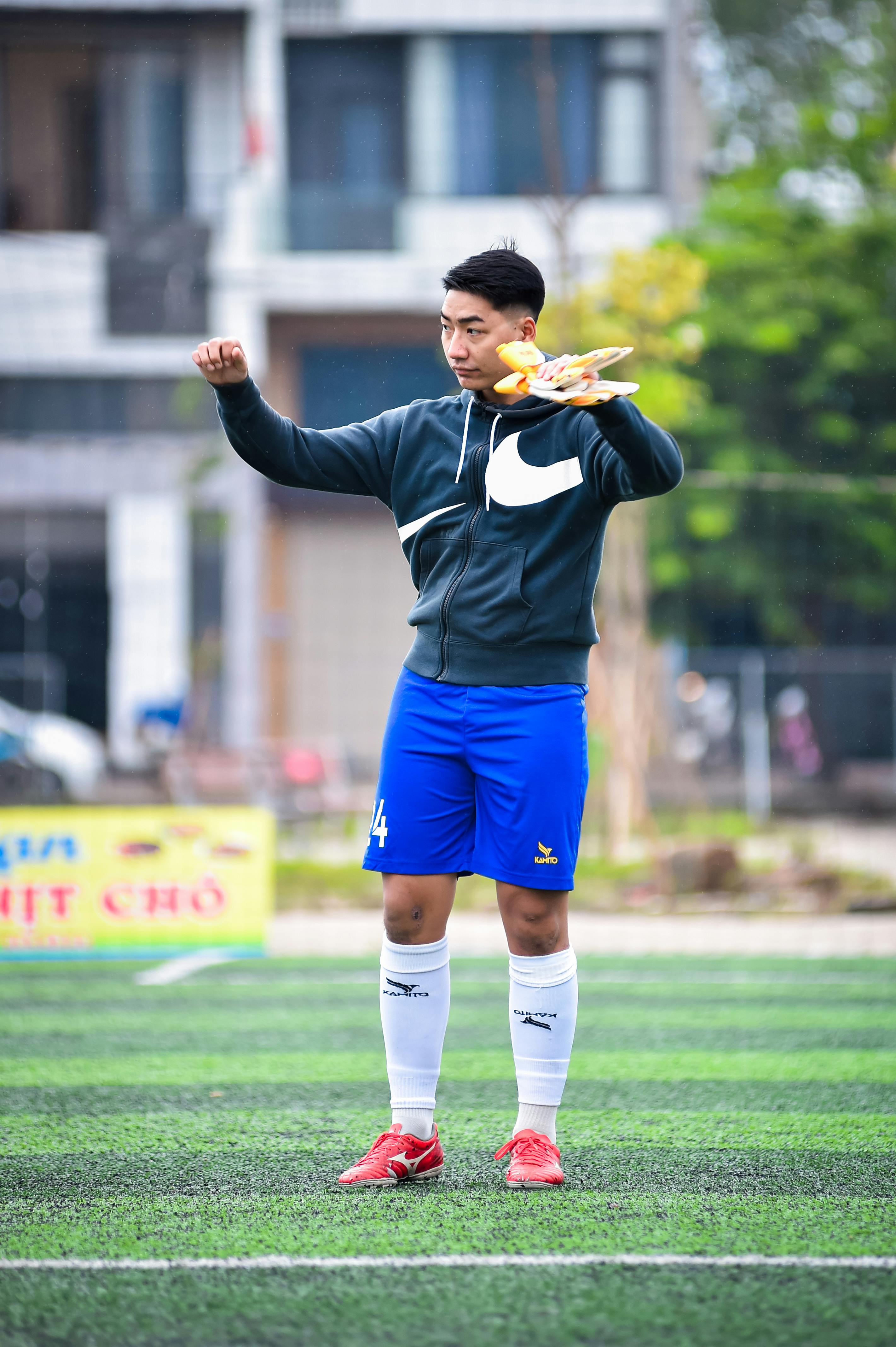 A focused football player warming up on an artificial turf field in Hanoi, Vietnam.