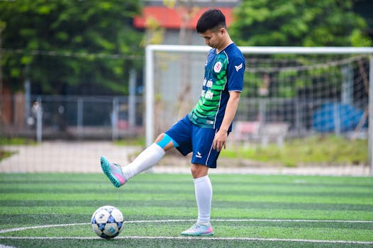 Teenage soccer player skillfully balancing a football on artificial turf in Hanoi, Vietnam.