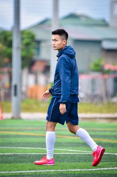 A young football player in athletic gear on an outdoor field in Hanoi, Vietnam.