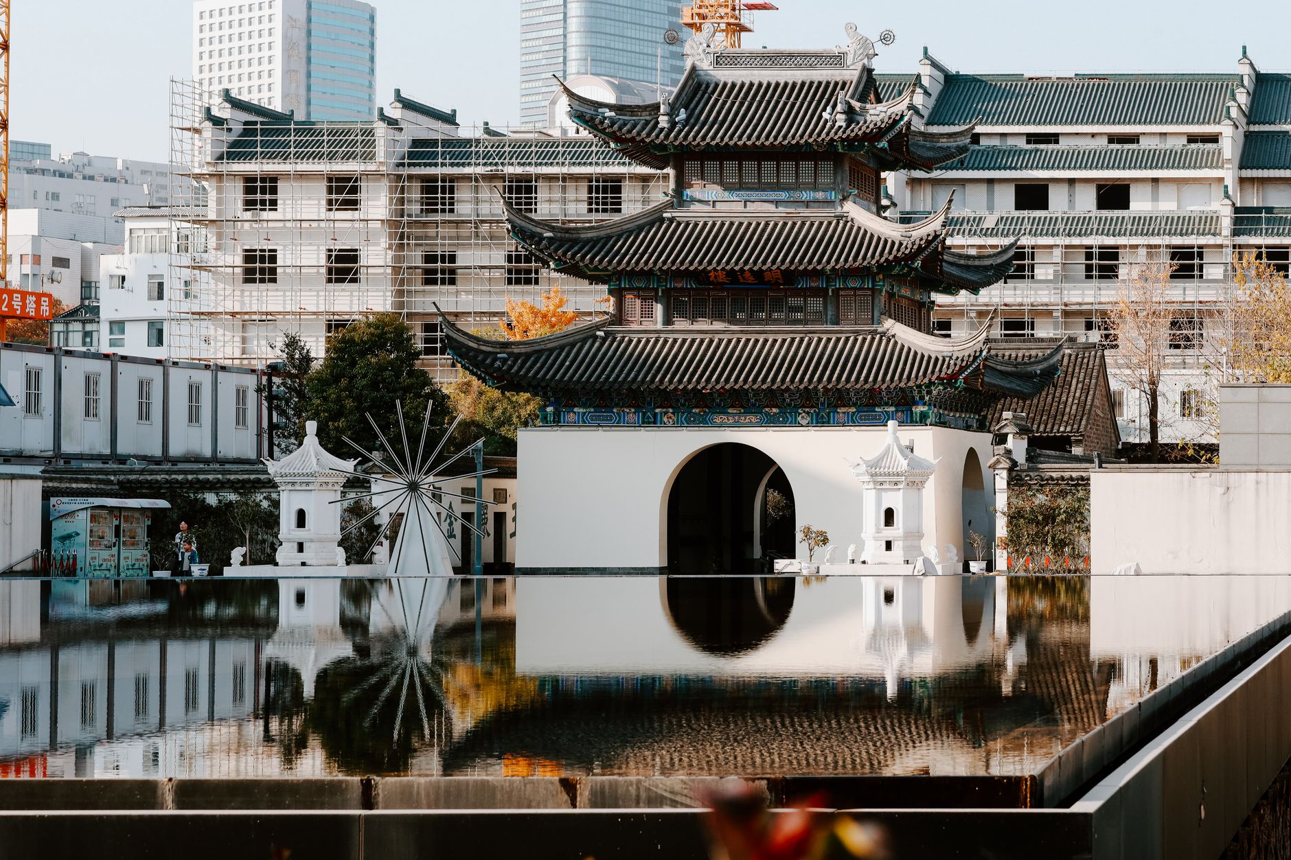 Nanjing's Confucius Temple surrounded by urban development and reflection in a serene pool.