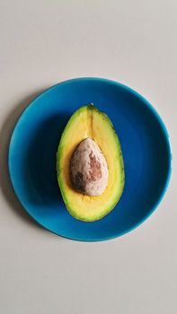 A fresh avocado half with seed on a blue plate, perfect for health and food themes.