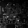 A high-contrast black and white close-up of a computer circuit board.