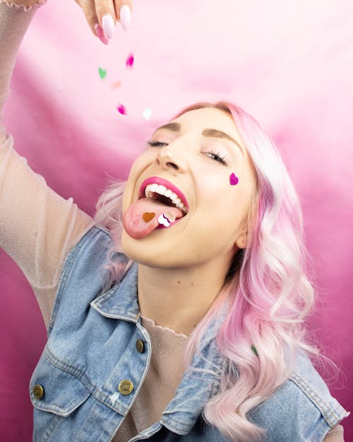 Woman Wearing Blue Denim Vest Standing While Eating Sweets