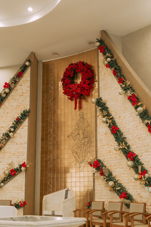 Free A church interior adorned with festive Christmas decorations featuring red wreaths and green garlands. Stock Photo