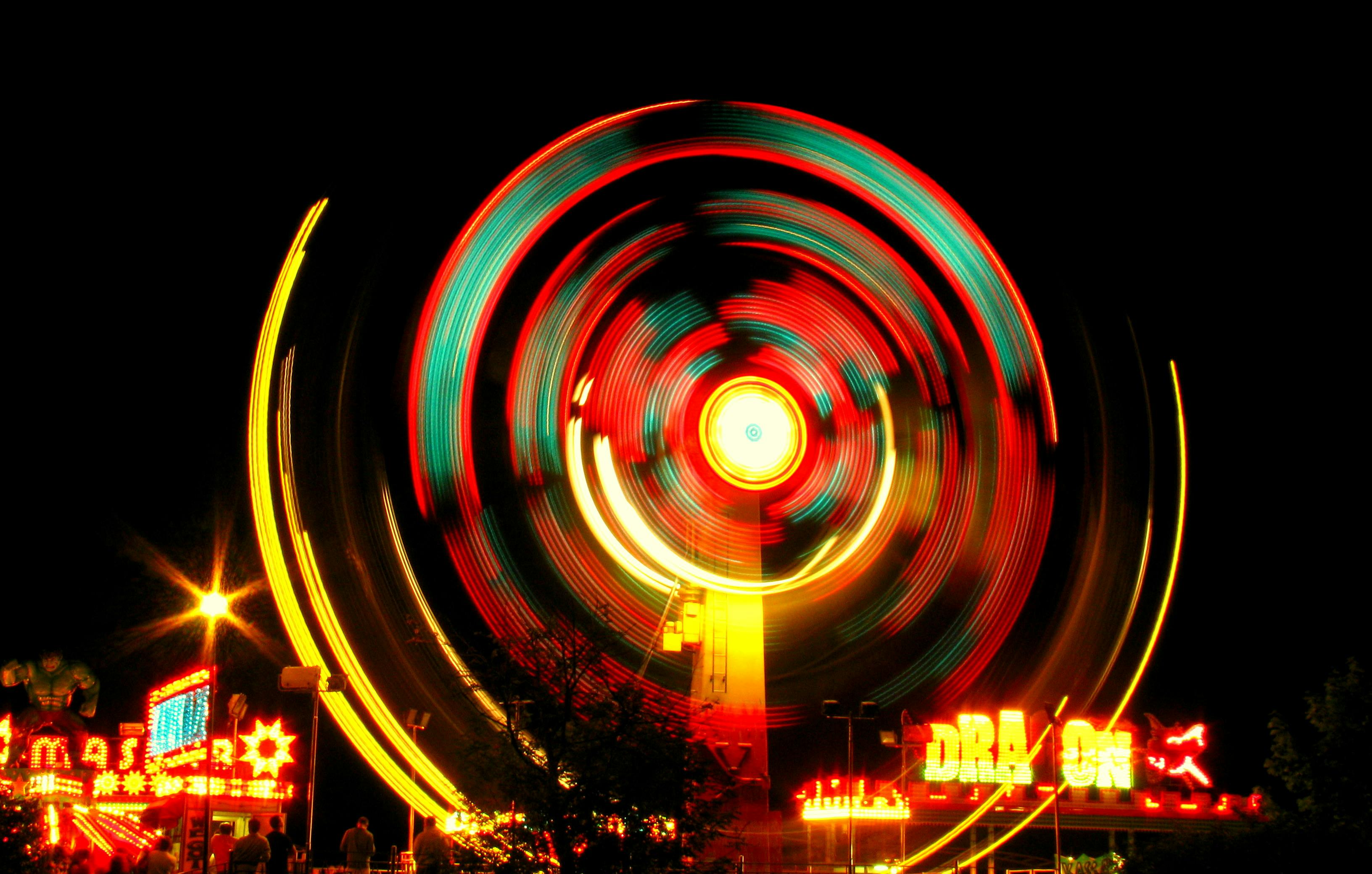 A colorful ferris wheel captured at night with vibrant glowing lights creating a circular motion blur.