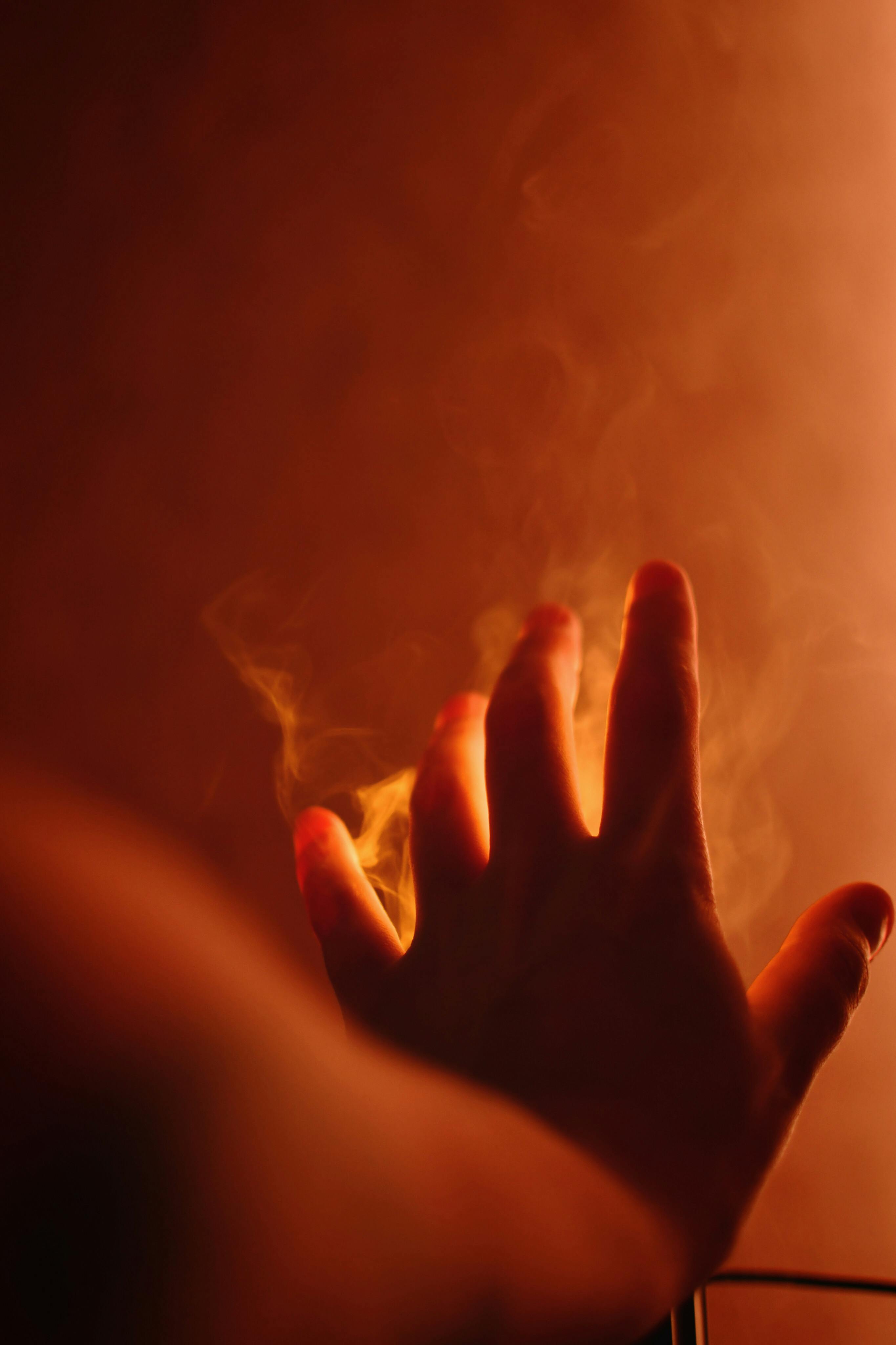 A mysterious hand reaches into warm, smoky light, creating an intriguing atmosphere.