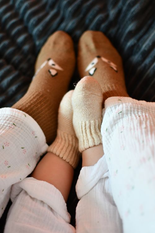 Free Cute family bonding moment with parent and baby's feet in cozy socks. Warmth and connection. Stock Photo