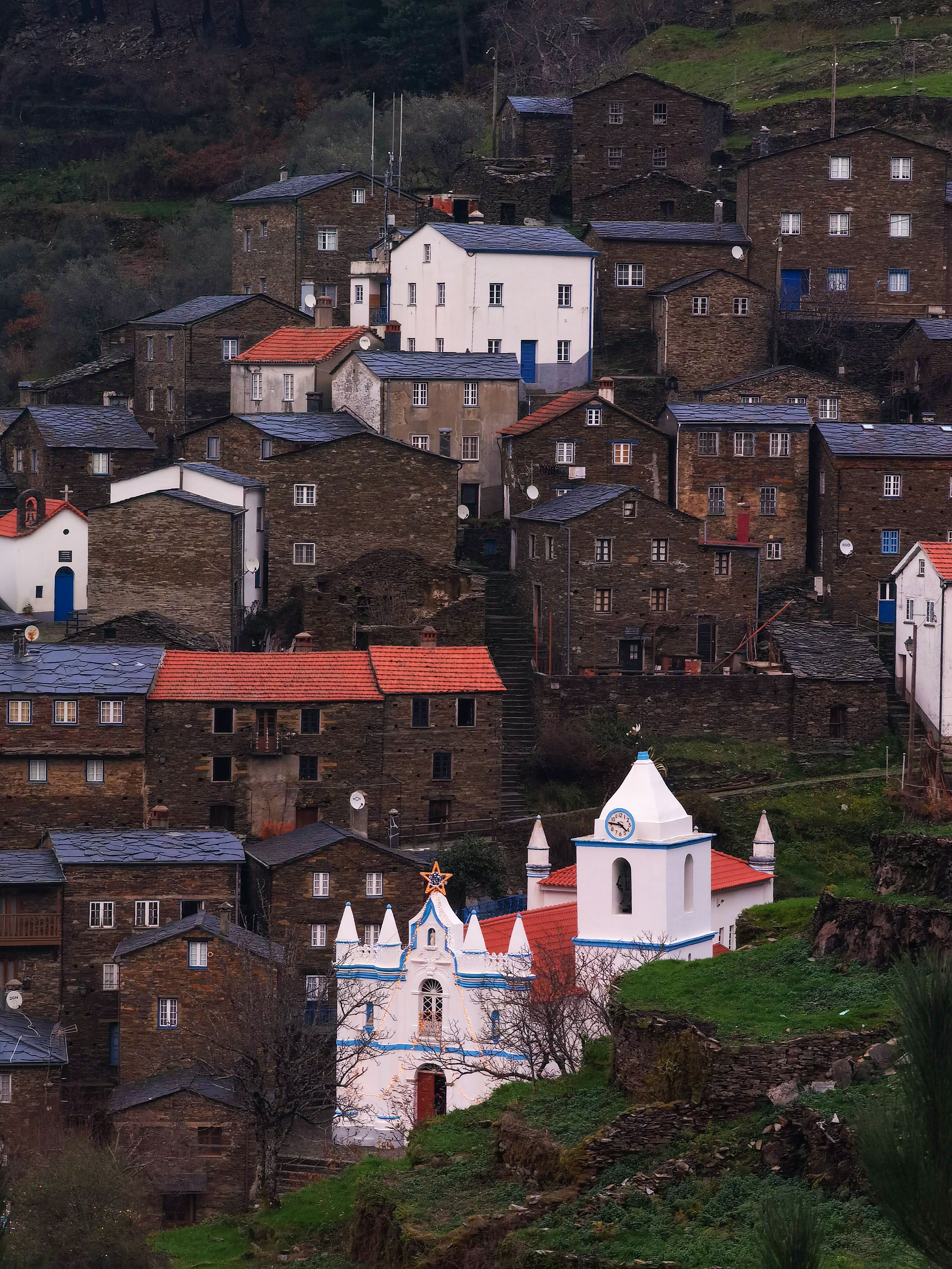 View of a rustic Portuguese village with traditional stone houses and a white chapel nestled in the mountains.