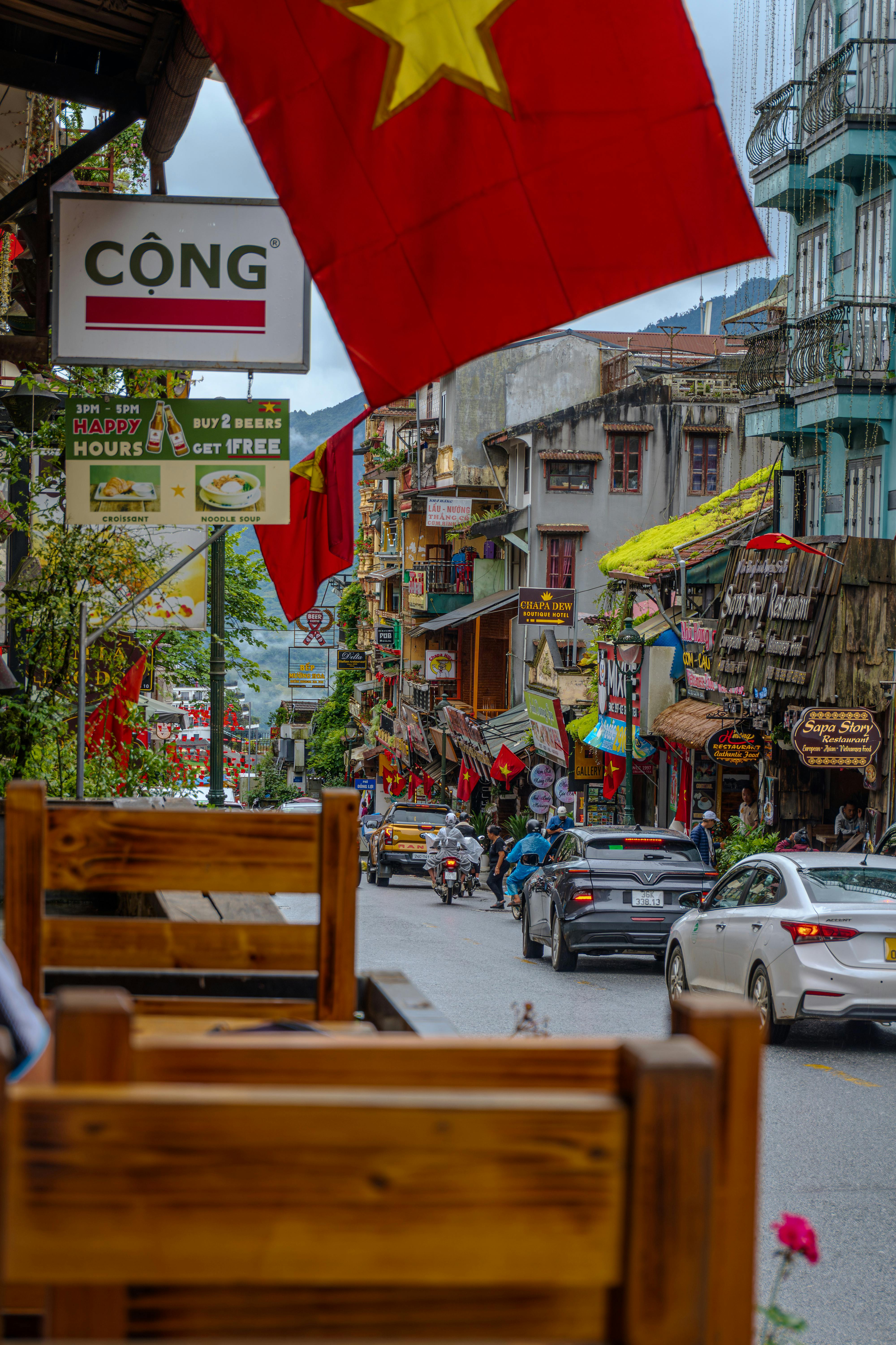 Bustling street in Vietnam with flags, signage, and vibrant local architecture.