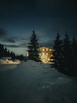 Cozy illuminated cabin in snowy Weißbach, Czech Republic night landscape.
