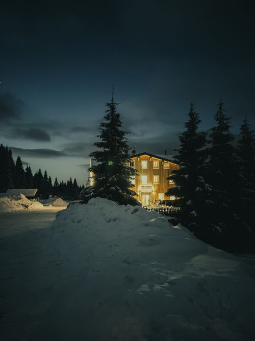 Free Cozy illuminated cabin in snowy Weißbach, Czech Republic night landscape. Stock Photo