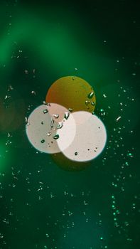 Abstract bokeh with droplets on glass, featuring green and warm-toned circles.
