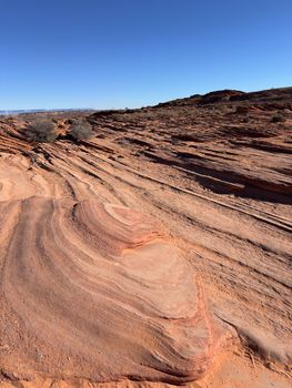 Explore the unique patterns of the Arizona desert's sandstone formations under clear blue skies.
