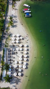Aerial shot of beach with umbrellas and boats docked on the shore in Bolívar, Colombia.