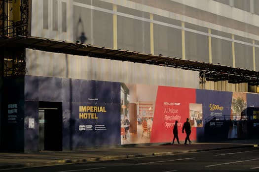 Construction site of Imperial Hotel in London with scaffolding and posters.