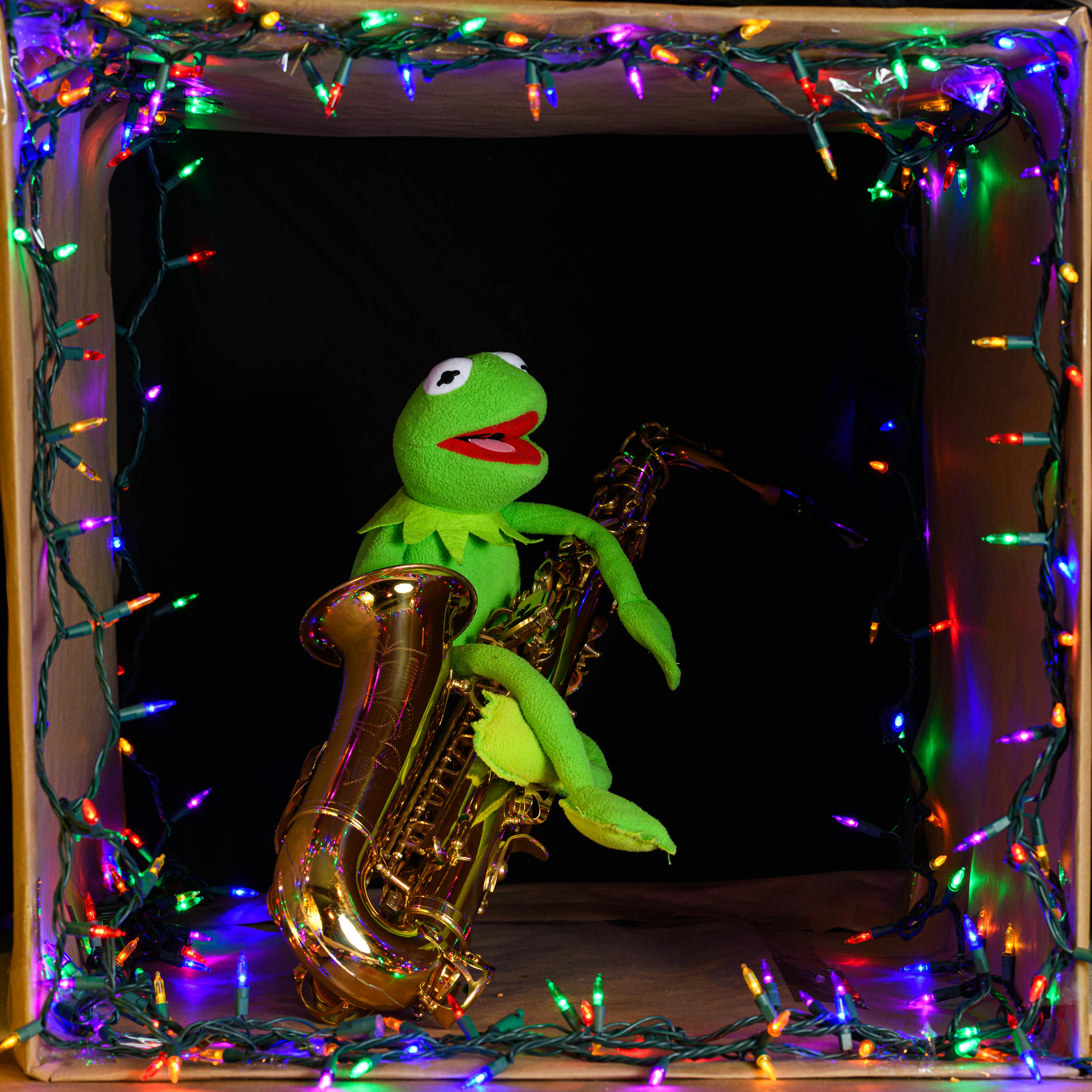 Vibrant puppet with a saxophone in a box adorned with festive lights.