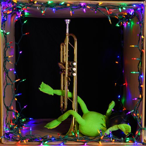 Free Creative shot of a trumpet surrounded by colorful festive lights and a green toy frog. Stock Photo