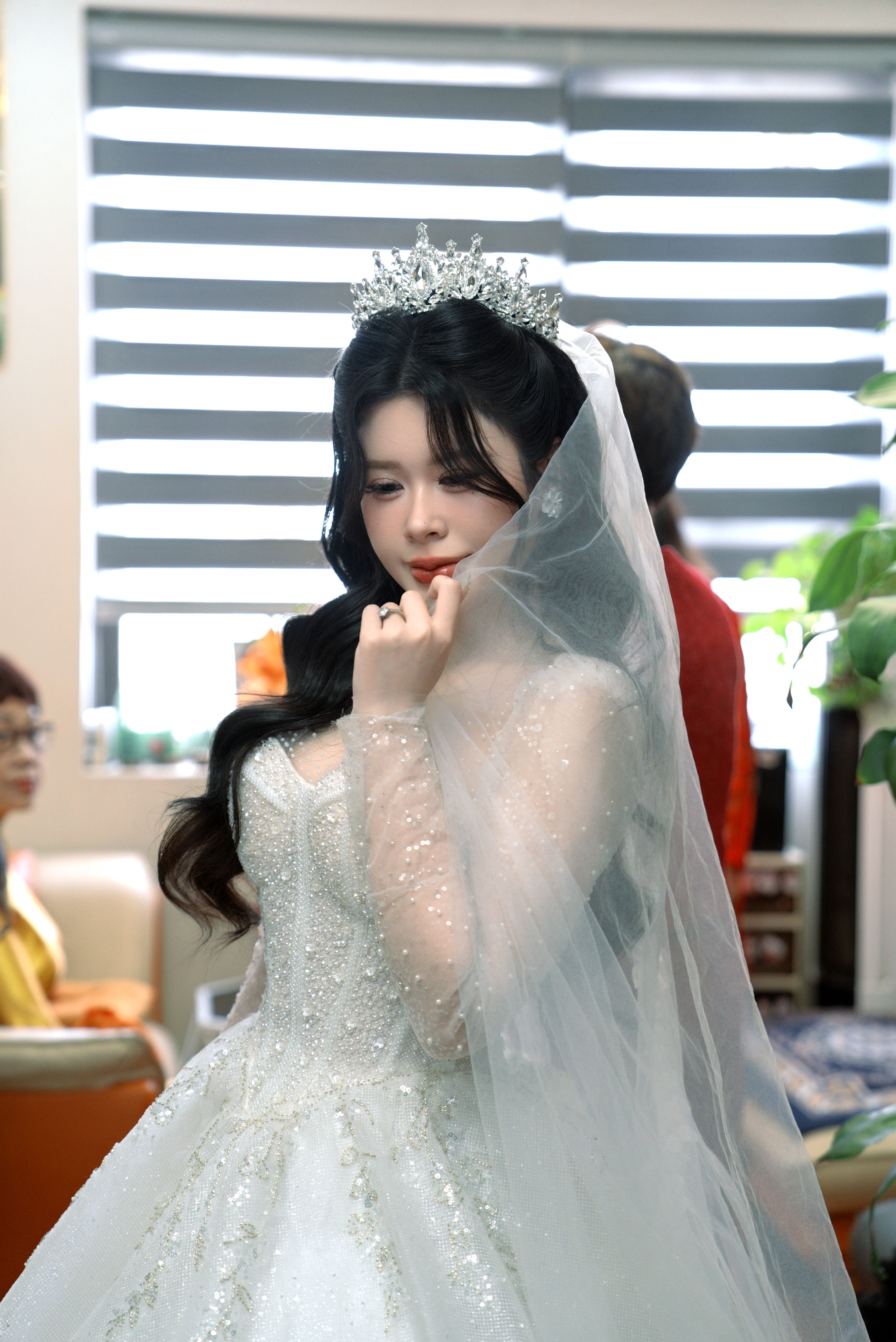 A beautiful bride in a sparkling white gown and tiara indoors, capturing grace and elegance.