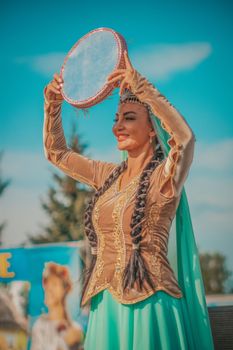 Colorful outdoor performance by a woman in traditional attire holding a tambourine. — photo by JB pictures