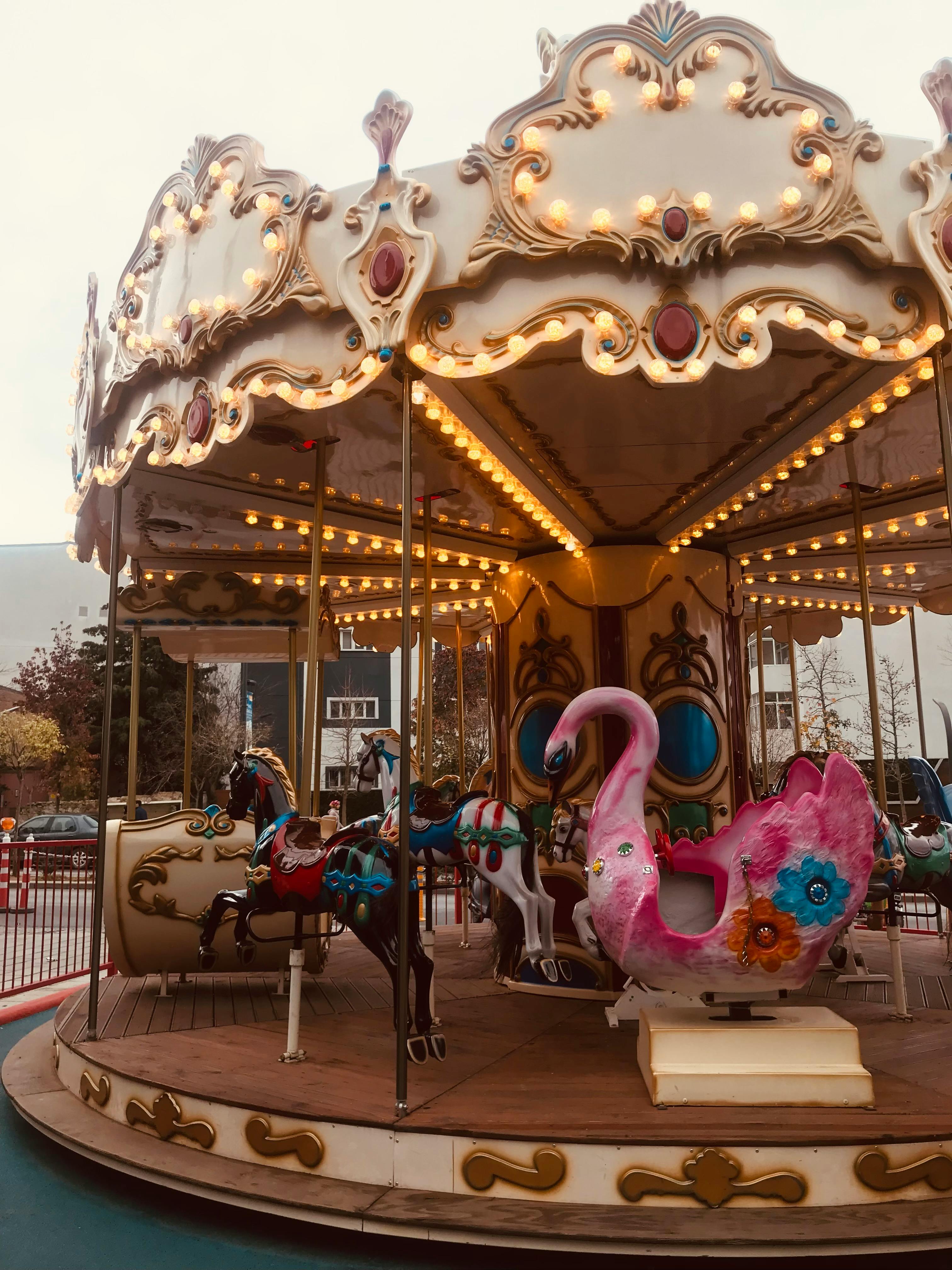 Charming vintage carousel with illuminated lights at an outdoor amusement park.