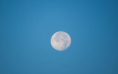 Free A clear view of the bright moon in a cloudless blue sky, showcasing its craters and details. Stock Photo