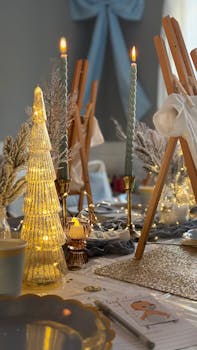 Cozy holiday table setting with warm candlelight, golden tree, and festive decor for a winter celebration.