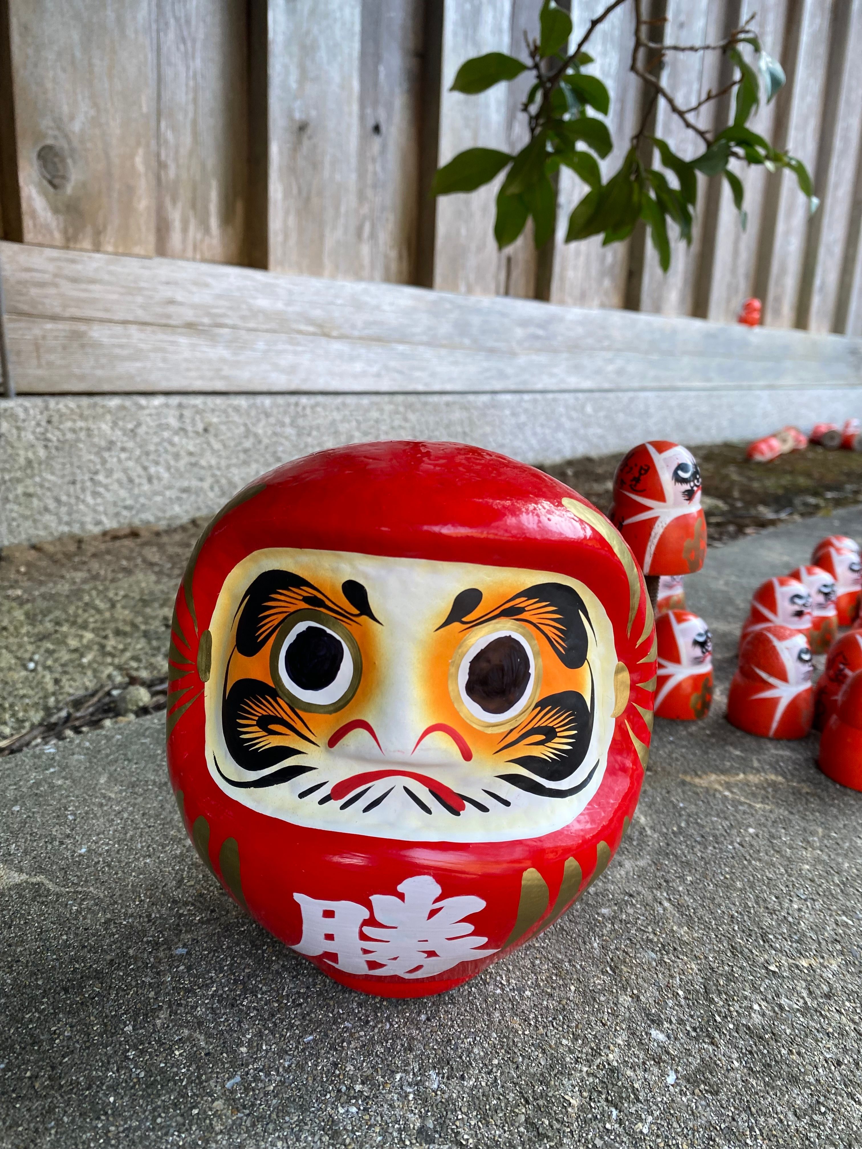 Rows of vibrant Daruma dolls outside, symbolizing perseverance and good luck in Japanese culture.