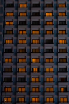 Evening view of a high-rise building facade with illuminated windows showcasing urban life at night.