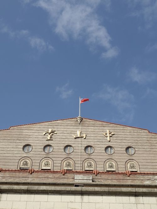 Free Vintage building facade with circular windows and flag against blue sky. Stock Photo
