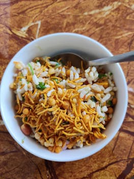 Crispy bhel puri snack mix served in a white bowl with spoon, ready to eat.