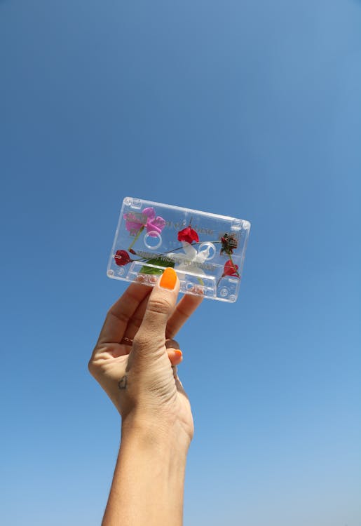 Person Holding White and Pink Floral cassette Tape
