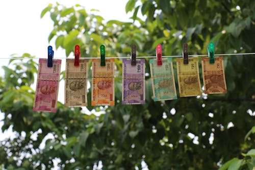 Free Seven Indian Rupee Banknotes Hanging from Clothesline on Clothes Pegs Stock Photo