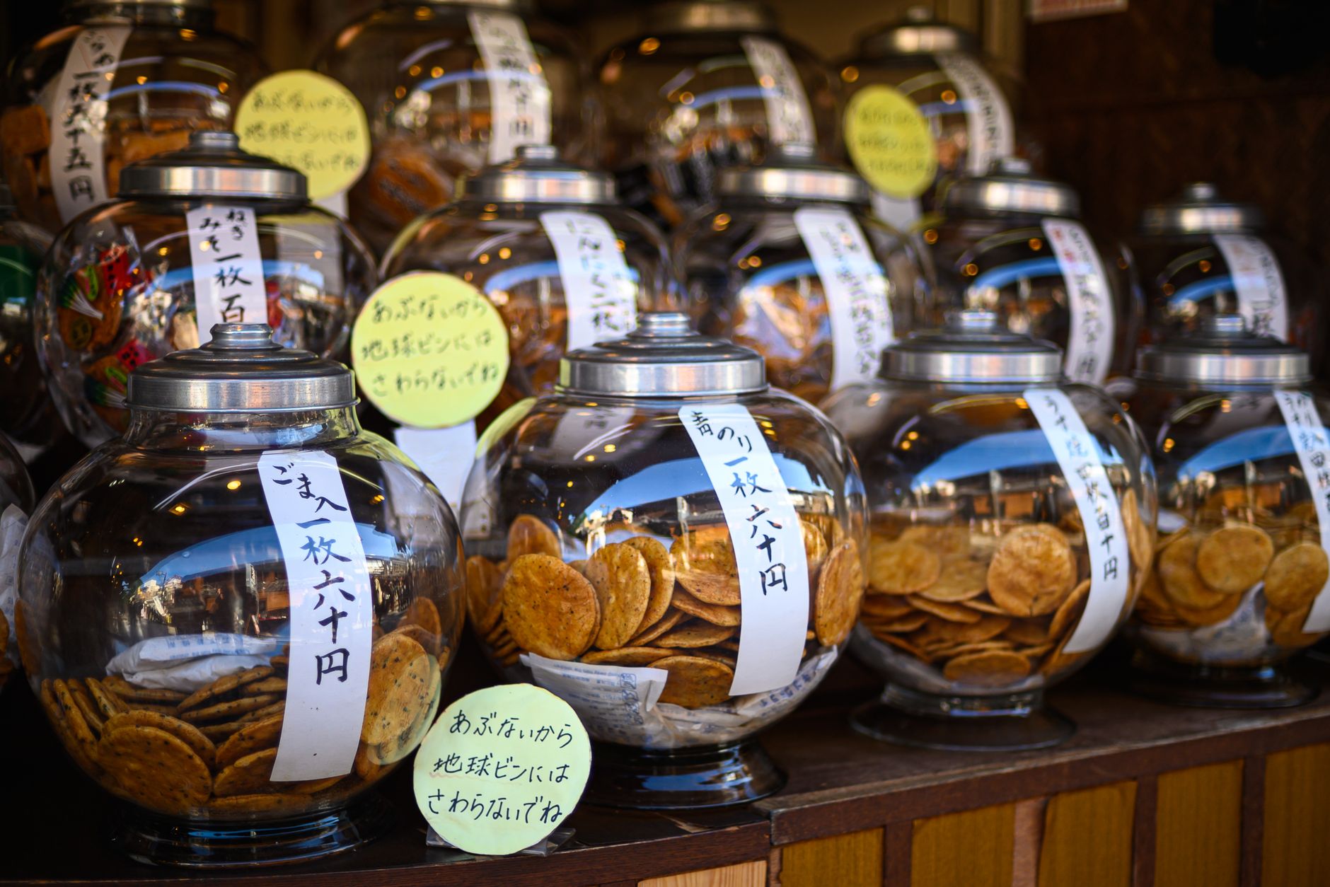 Rows of senbei rice crackers in glass jars, showcasing Japan's traditional snacks.