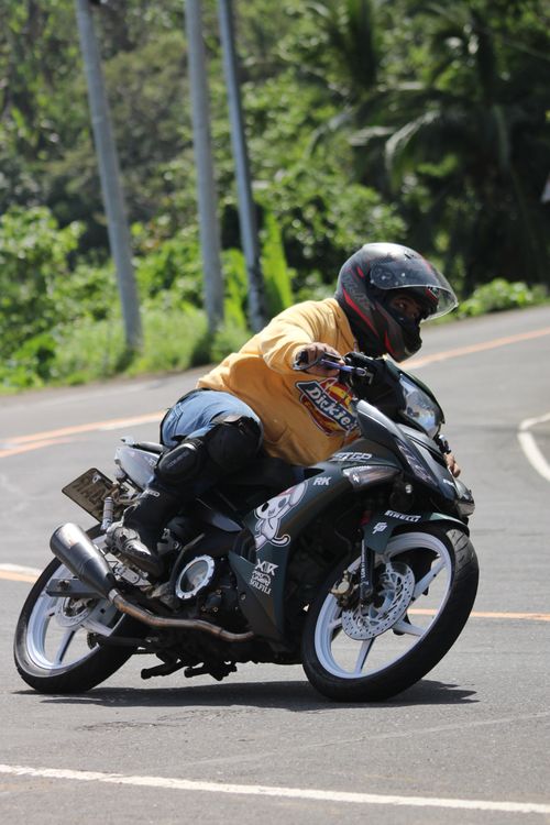 Free Motorcyclist wearing safety gear takes a sharp turn on a scenic, lush road. Stock Photo