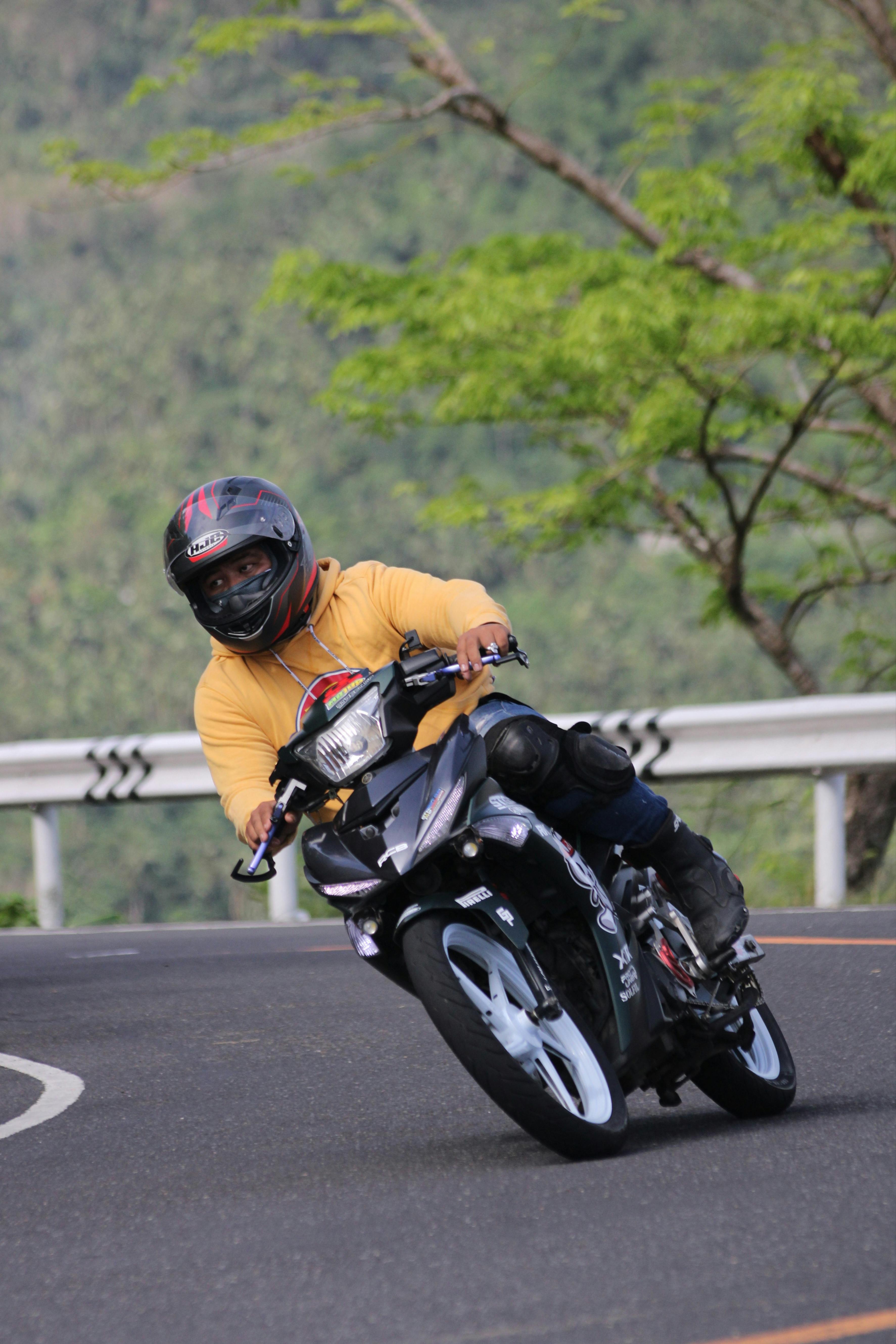 A motorcyclist skillfully leans into a sharp mountain curve, showcasing riding prowess.