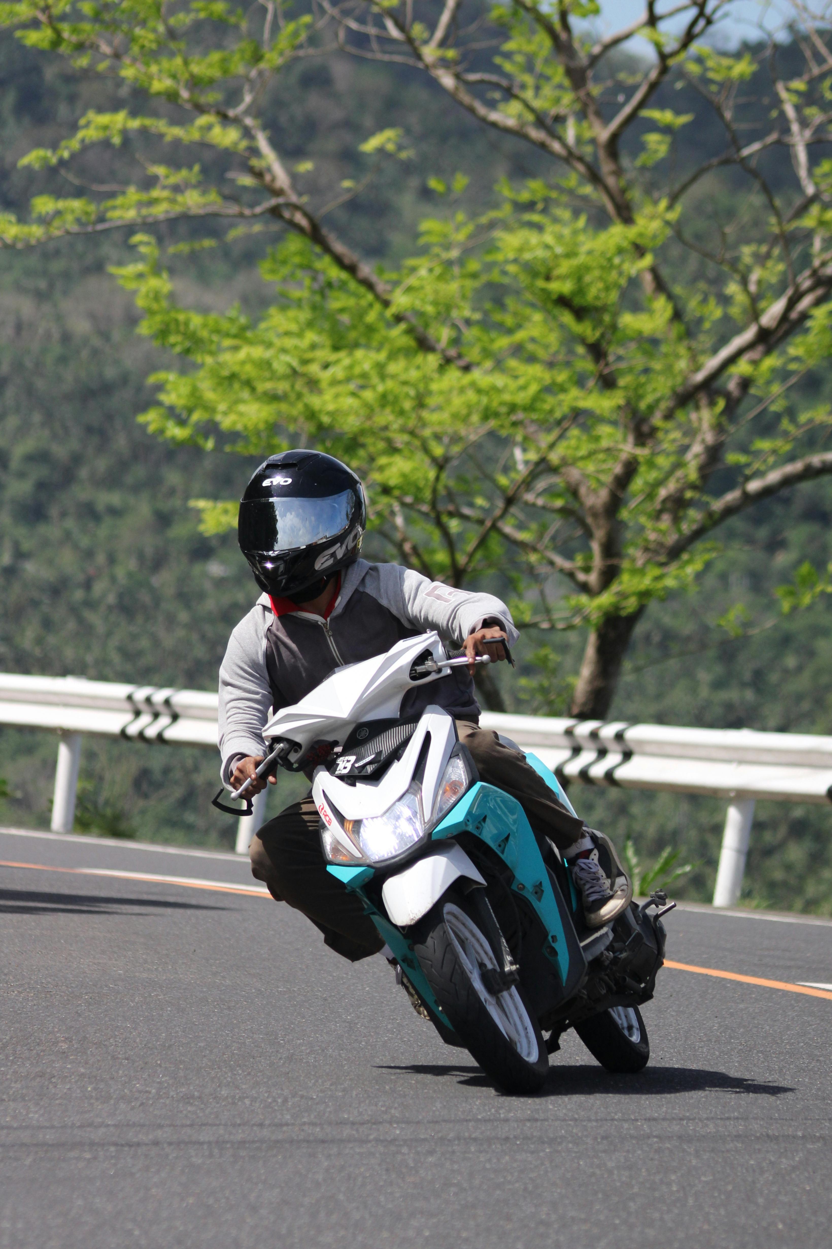 A motorcyclist skillfully leans into a curve on a sunny mountain road.