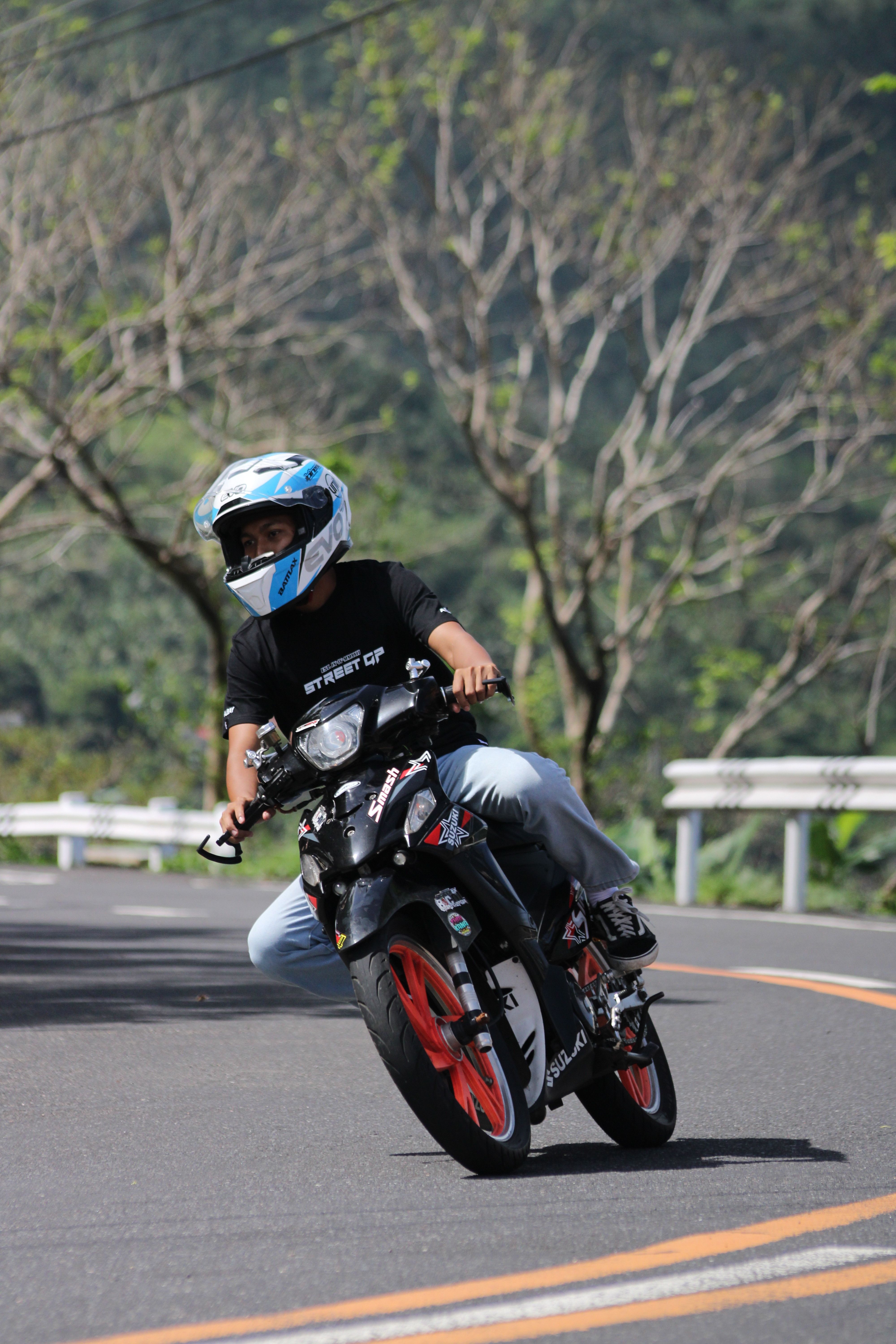 Adult motorcyclist leaning into a turn on a scenic winding road, wearing protective gear.