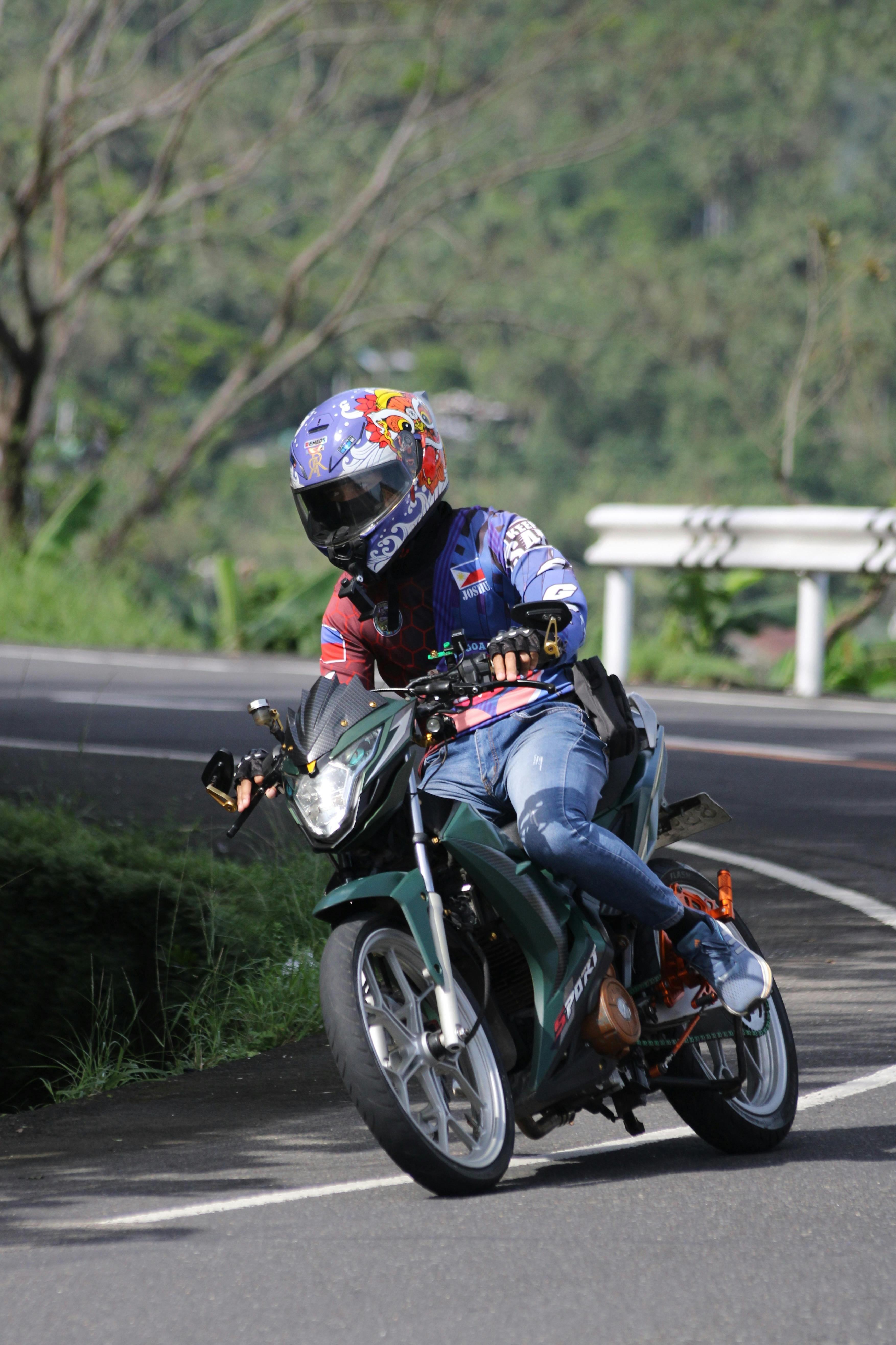 Motorcyclist expertly maneuvers a curve on a scenic, winding outdoor road.