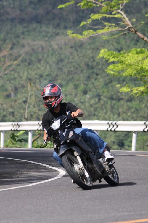 Free Motorcyclist on a winding mountain road, showcasing skillful leaning into a sharp curve. Stock Photo