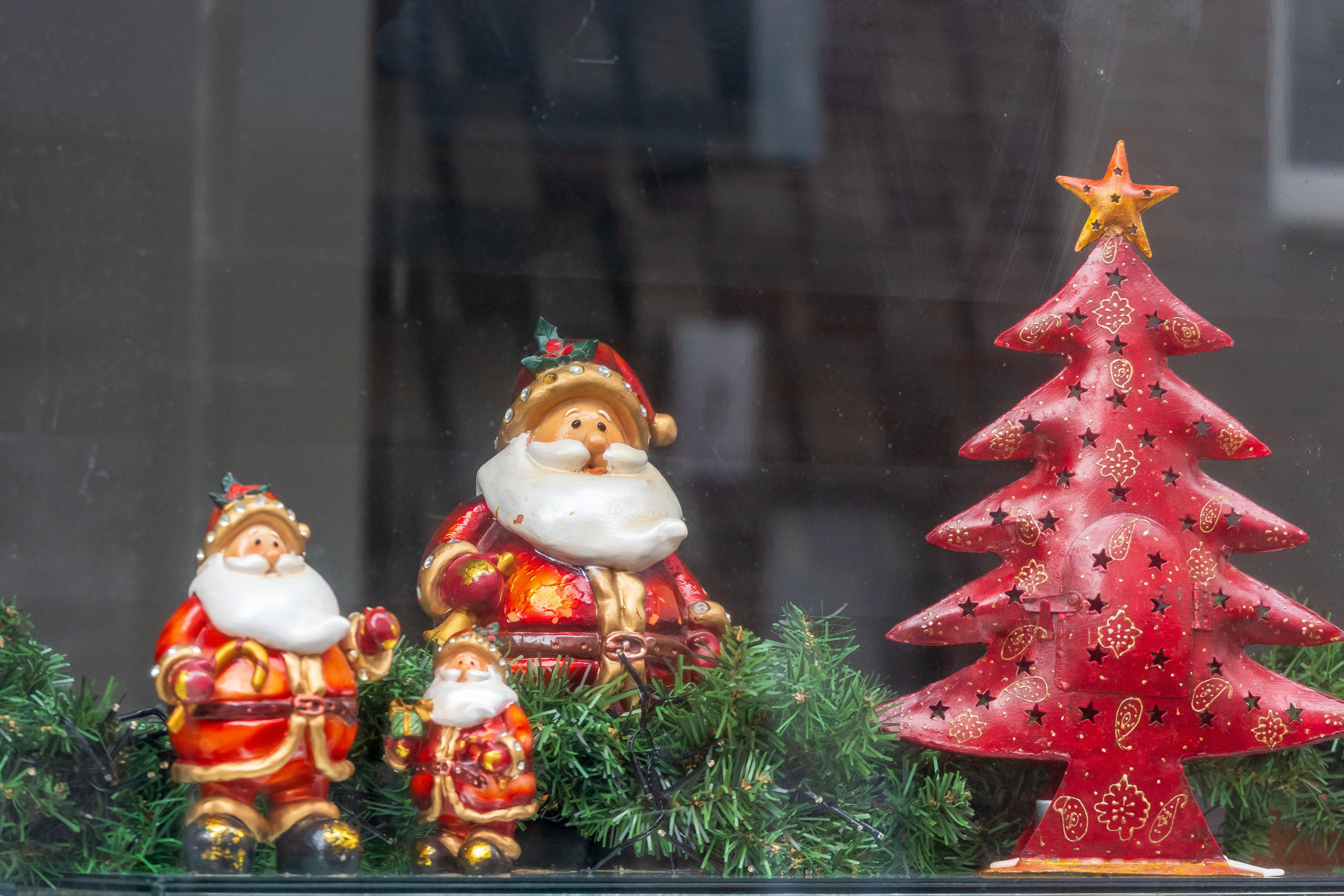 Zadarmo Rozkošné keramické figúrky Santa Clausa vedľa ozdobného červeného vianočného stromčeka. Fotka z fotobanky