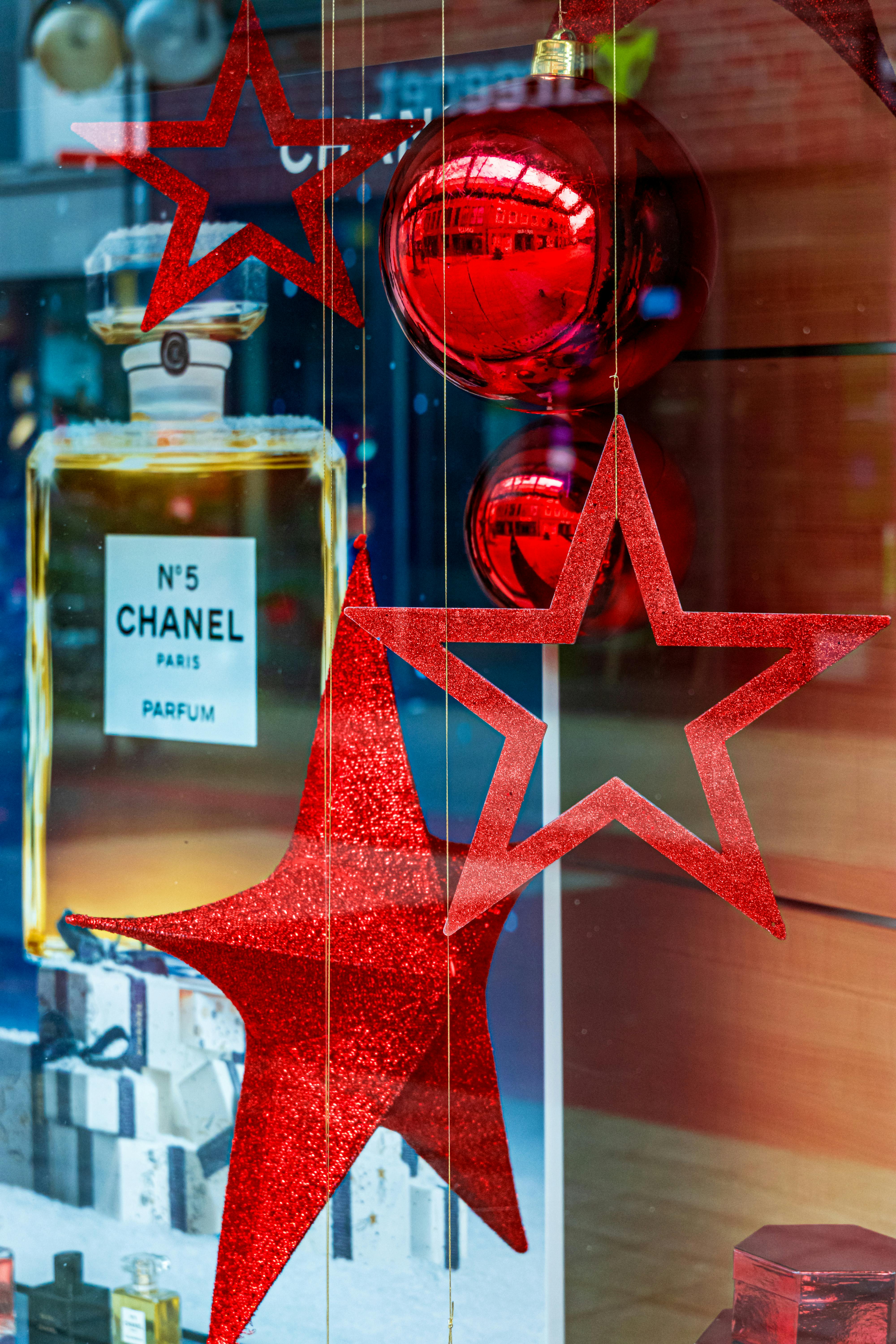 Vibrant red stars and ornaments decorate a store display with Chanel No.5 bottle.