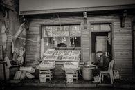 A black and white photo of a vendor at an outdoor fish market stall, showcasing fresh fish.