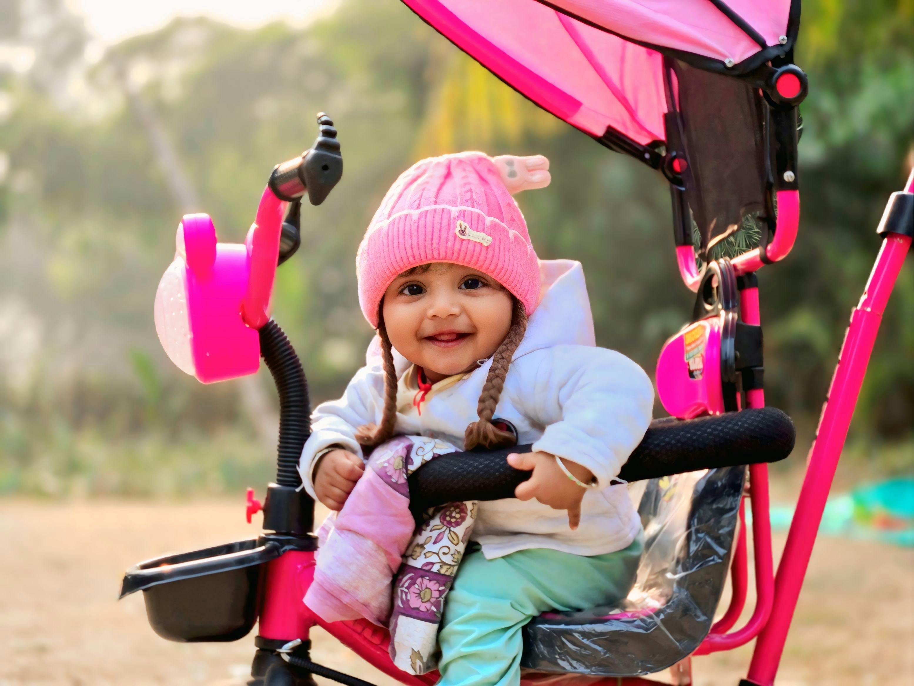 A smiling baby in a stroller enjoying an outdoor photoshoot in Rupsa, India.