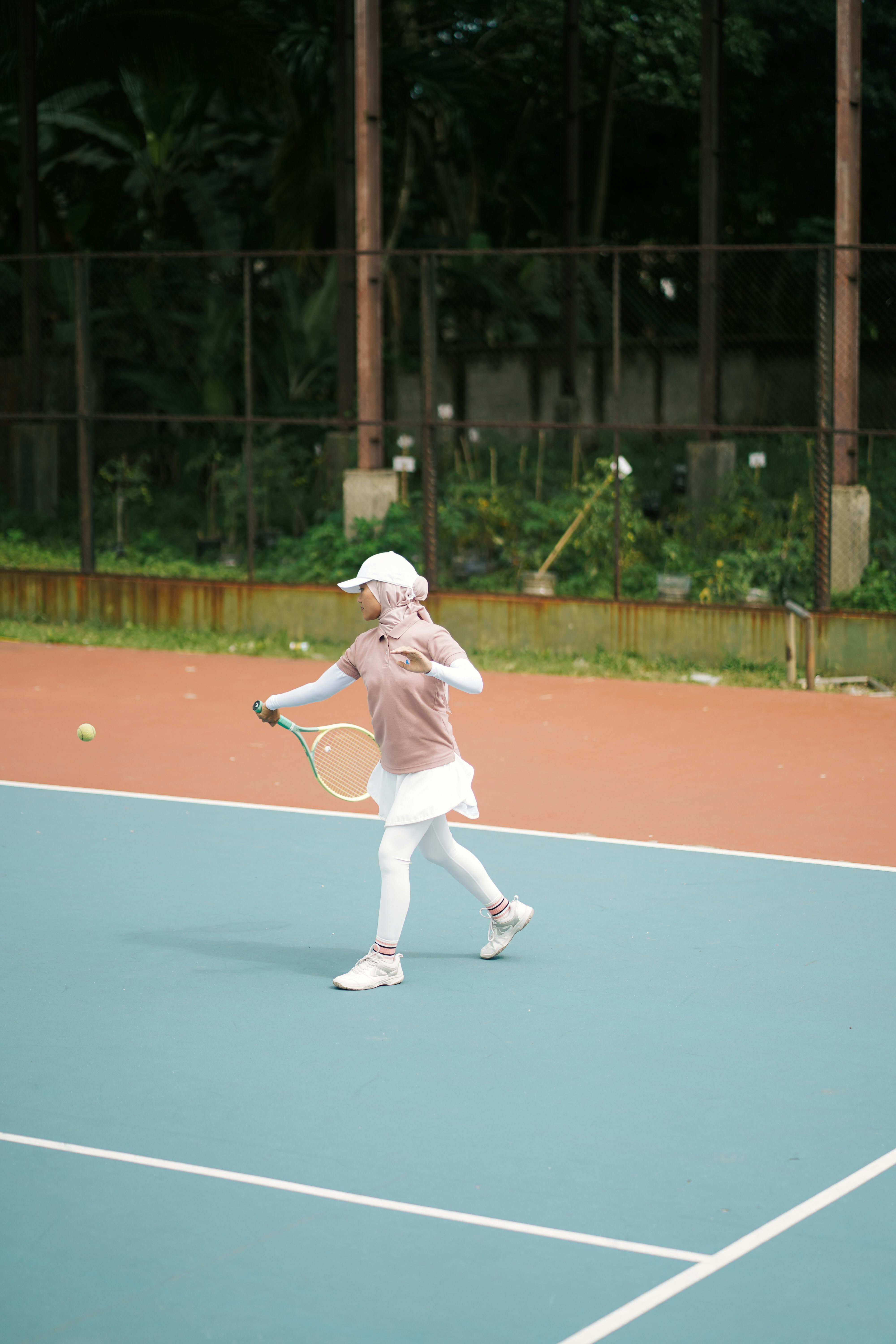 Female tennis player in motion on an outdoor court, focusing on gameplay.