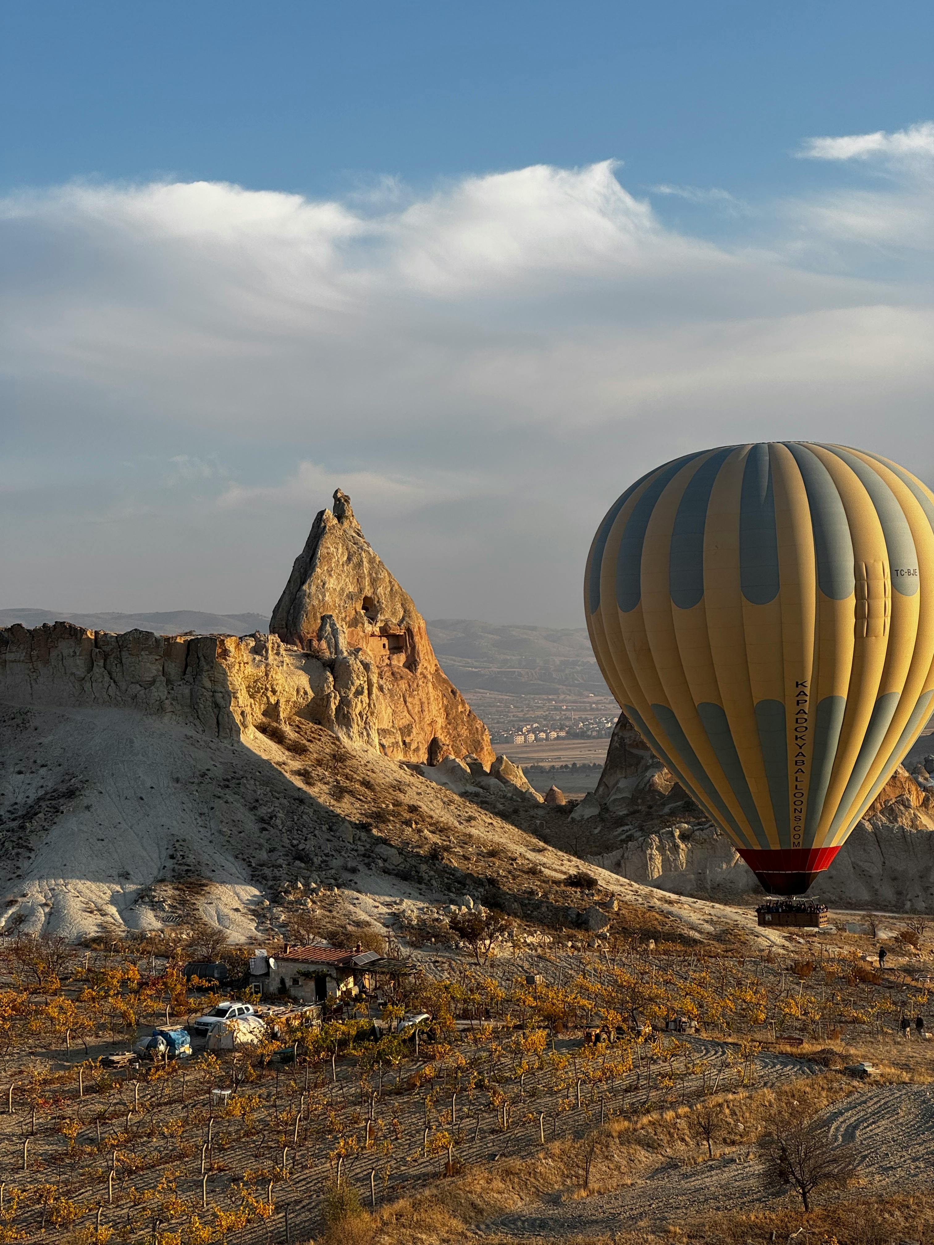 Hot air balloon soaring over Cappadocia's distinctive rock formations at sunrise.