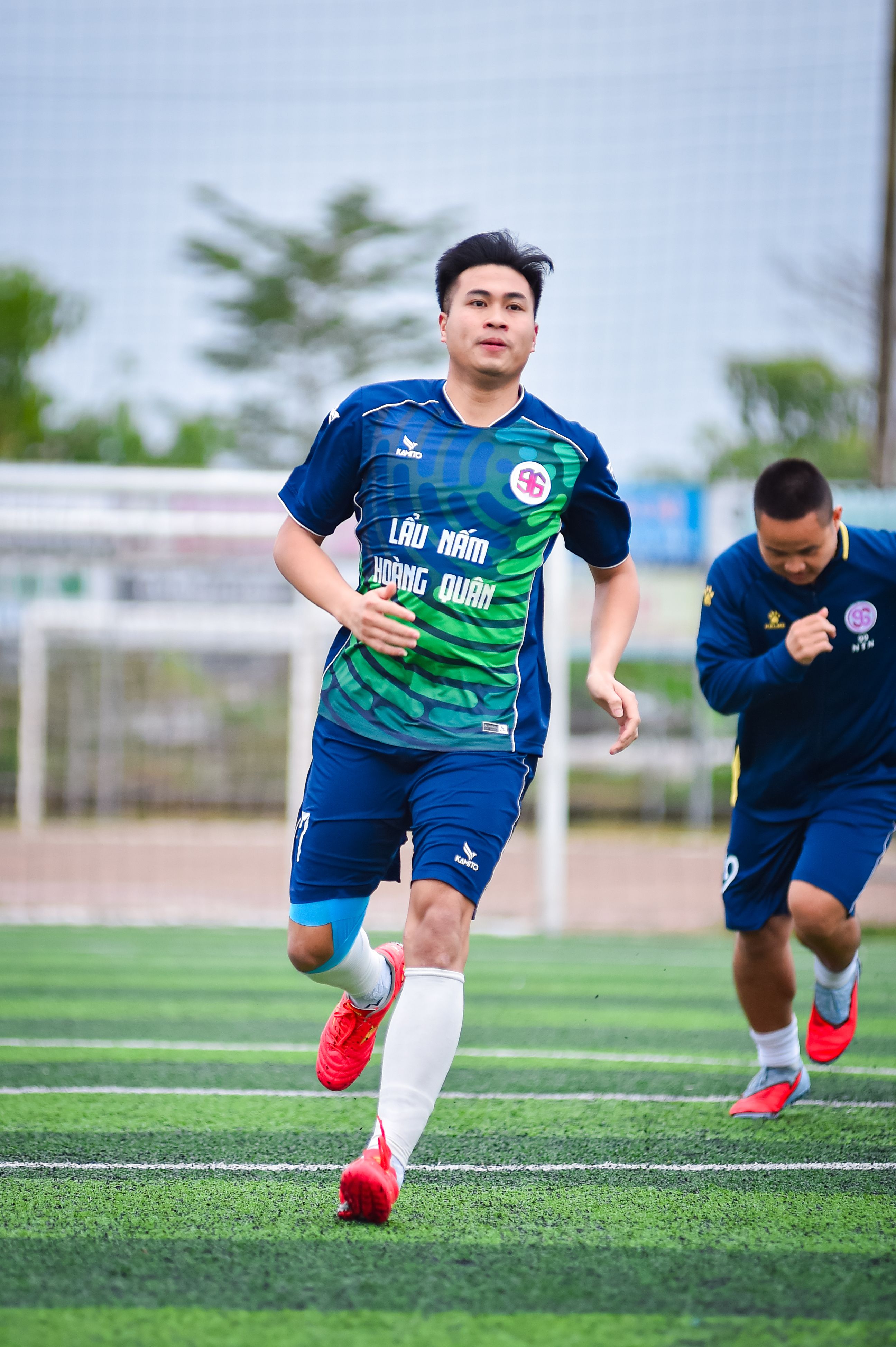 Two male football players in action on an outdoor turf field in Hà Nội, Việt Nam.