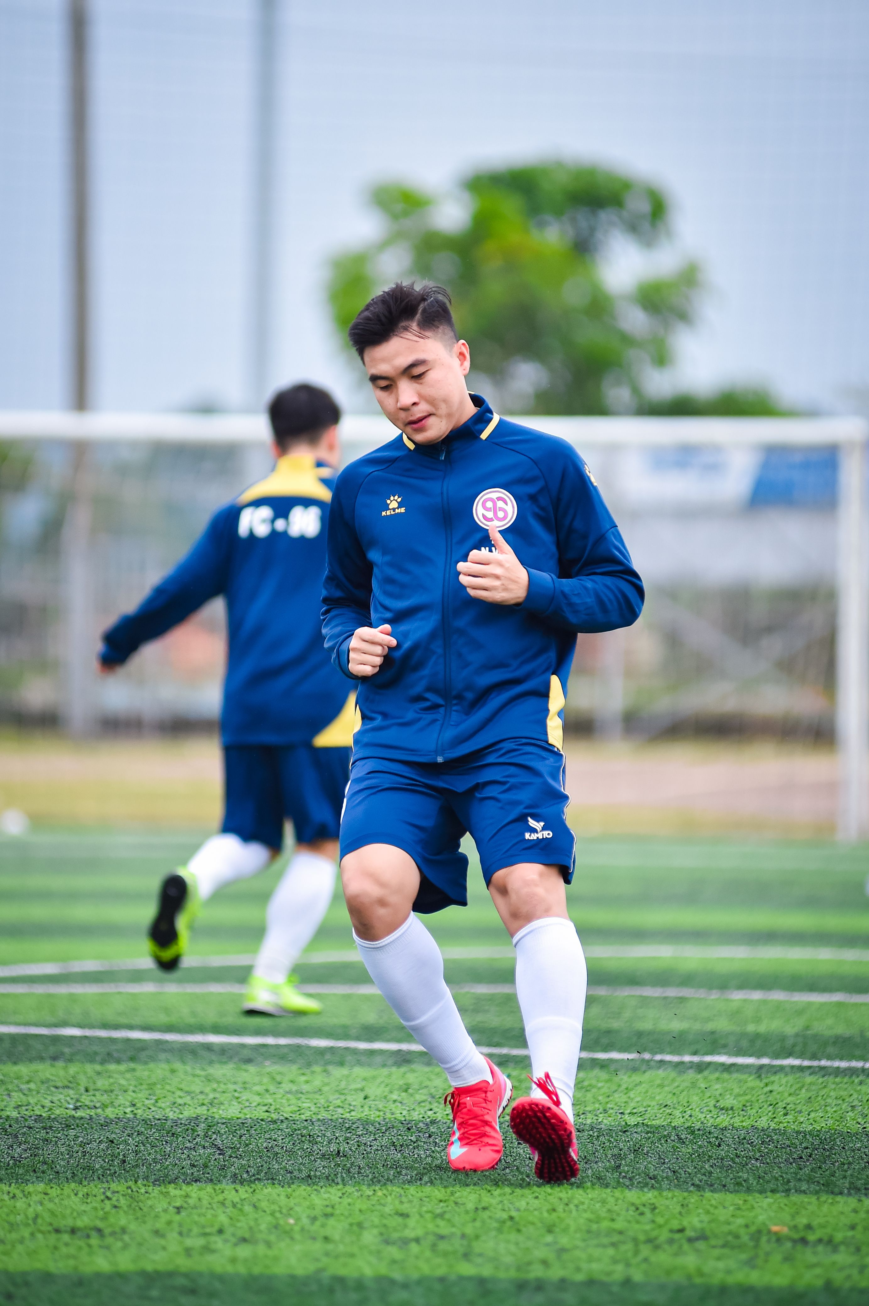 Asian football players practicing on artificial turf field, showcasing team spirit and athleticism.